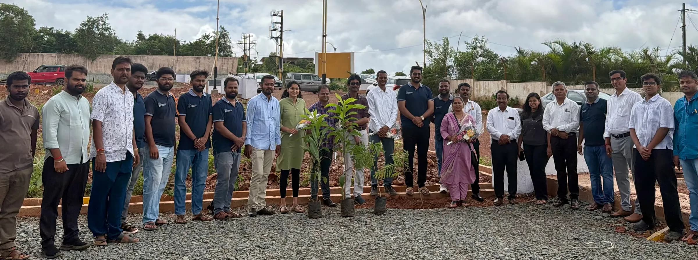 The Apollo team and guests gathered around newly planted saplings at a planting drive